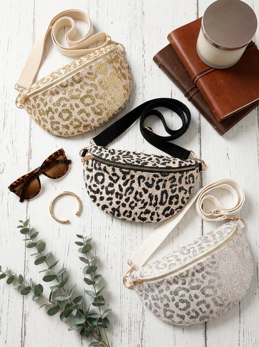 Leopard print fanny packs, sunglasses, and a candle on a white surface