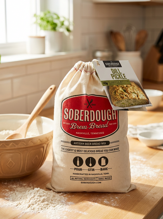 Bag of Soberdough brew bread mix on a kitchen counter with a bowl of flour and wooden spoon.