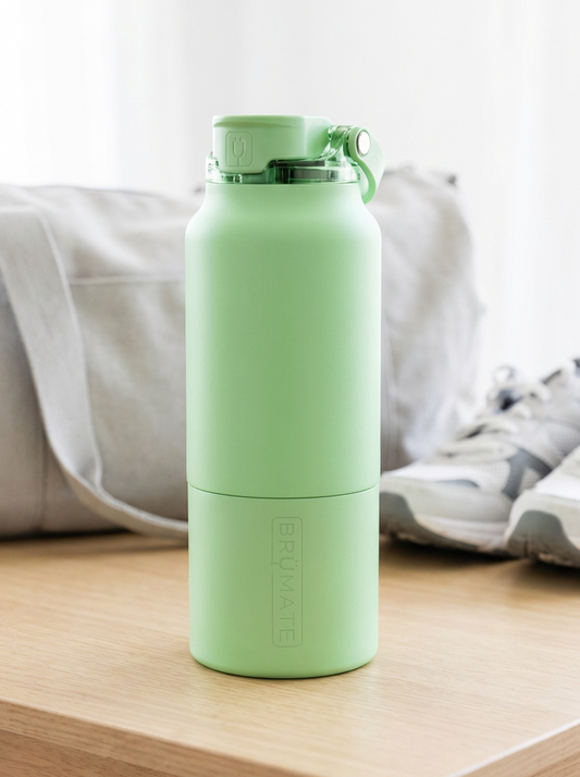 Green water bottle on a wooden table with a blurred background